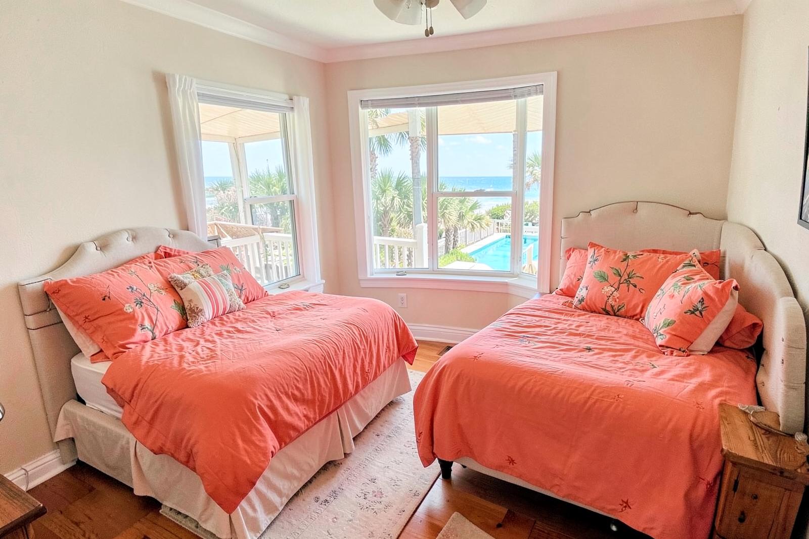 Twin bedroom with coral bedding and pool views